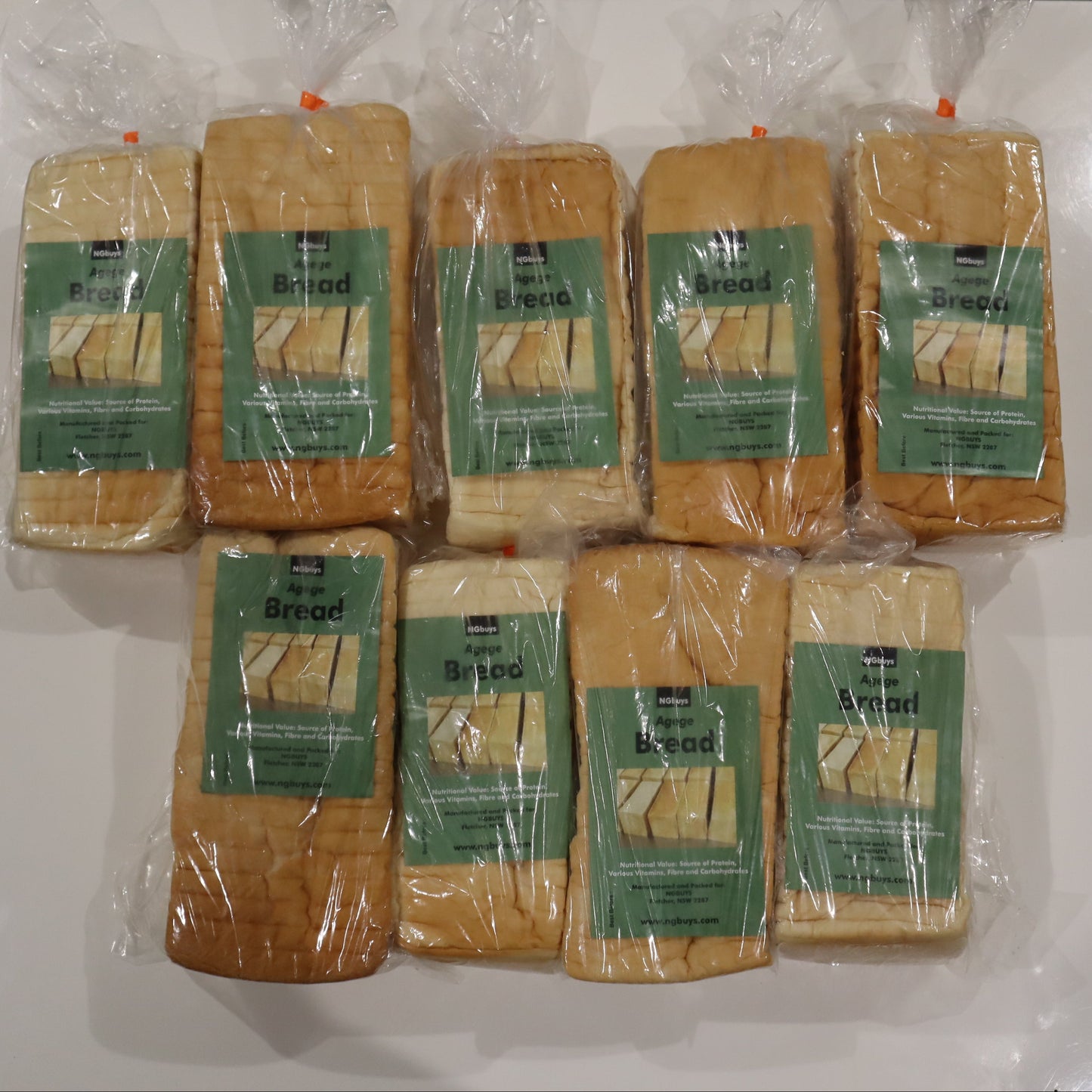 Multiple packages of bread with green labels on a white surface