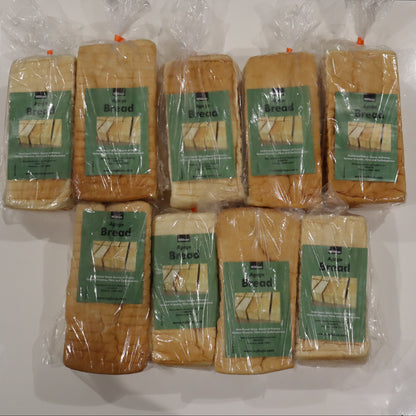 Multiple packages of bread with green labels on a white surface