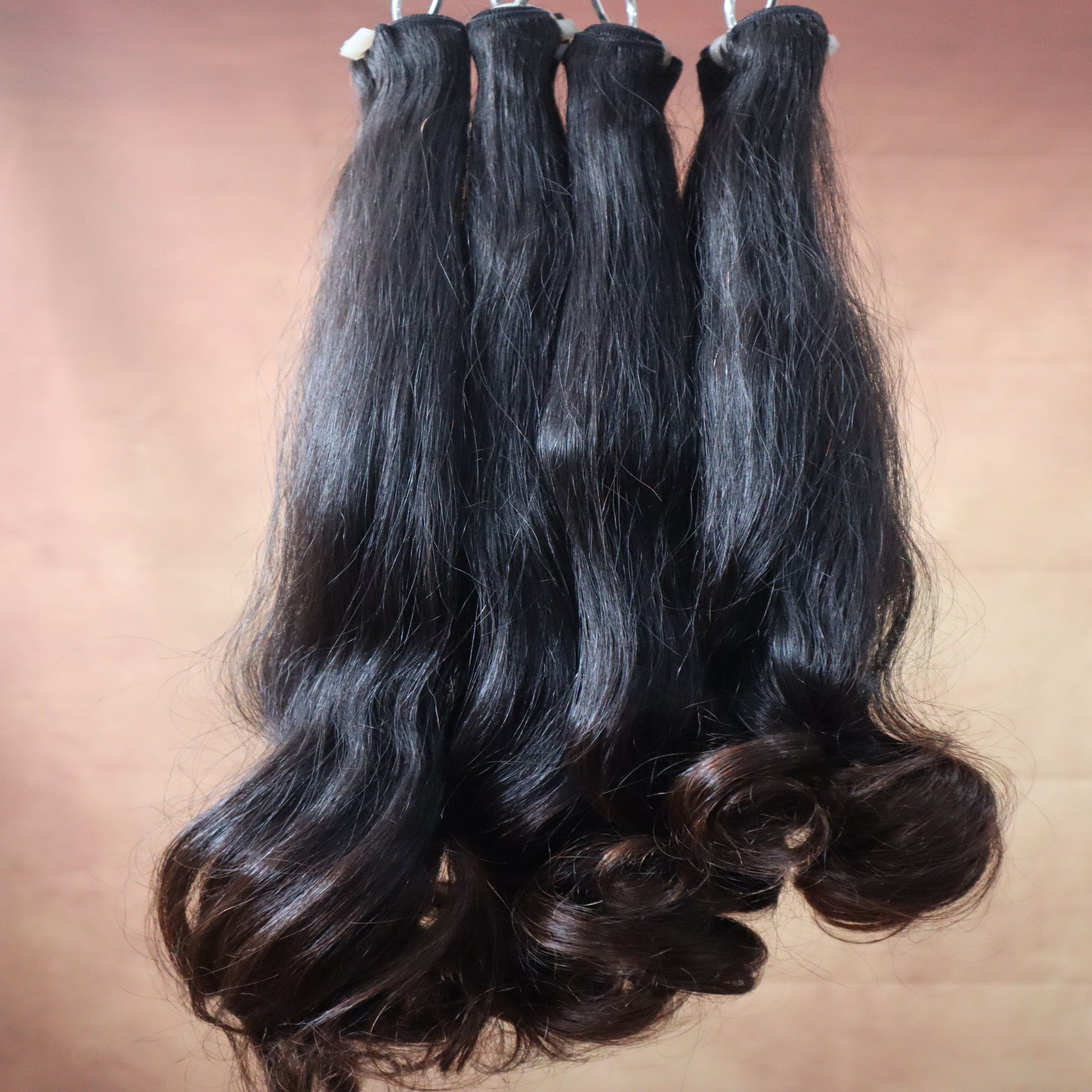 Three bundles of black hair extensions on a brown surface
